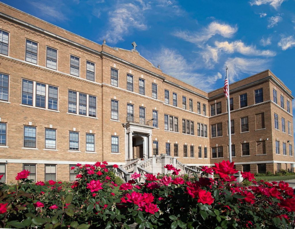 Guardian Angel Hall building at St. Clare Campus, with fuchsia roses in front