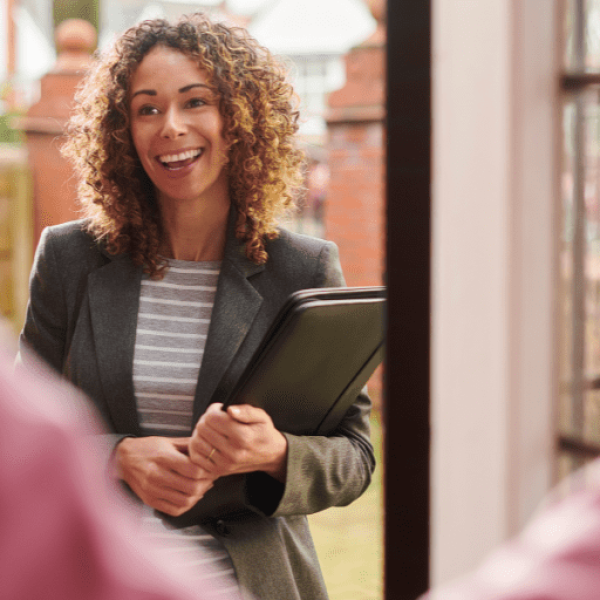 smiling female social worker standing in a doorway of a home